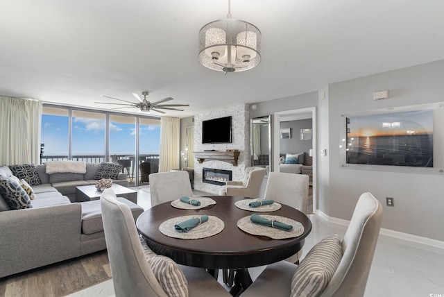 dining area with light hardwood / wood-style flooring, a fireplace, expansive windows, and ceiling fan