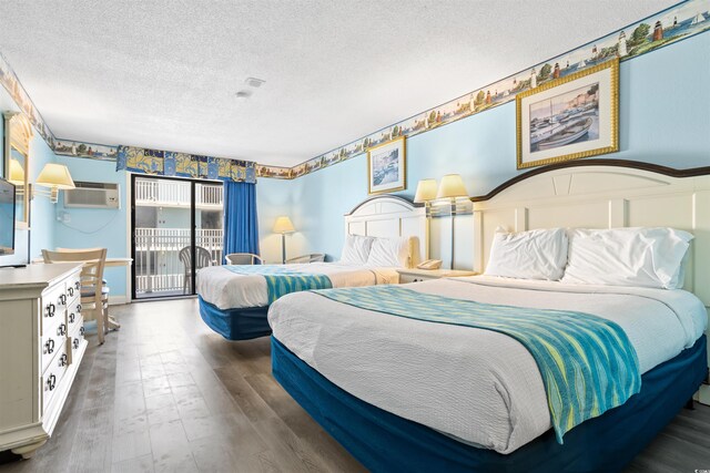 bedroom with a wall mounted AC, wood-type flooring, access to exterior, and a textured ceiling