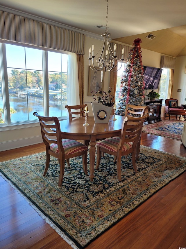 dining space featuring crown molding, wood-type flooring, and an inviting chandelier