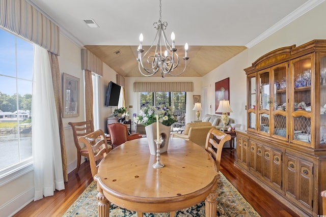 dining room featuring hardwood / wood-style floors, ornamental molding, vaulted ceiling, and an inviting chandelier