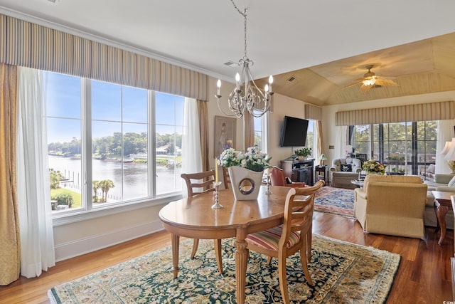 dining area with hardwood / wood-style floors, a water view, a healthy amount of sunlight, and vaulted ceiling