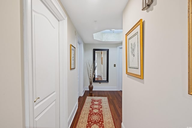 corridor with dark hardwood / wood-style flooring and a skylight