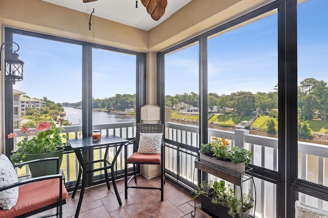 sunroom with a water view and ceiling fan