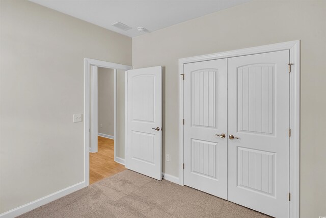 unfurnished bedroom featuring light carpet and a closet