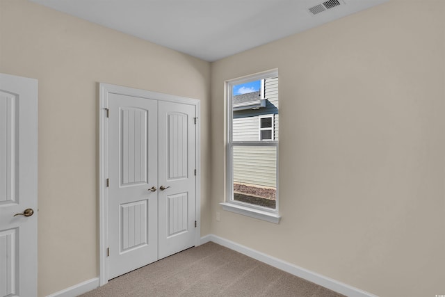 unfurnished bedroom featuring multiple windows, a closet, and light colored carpet