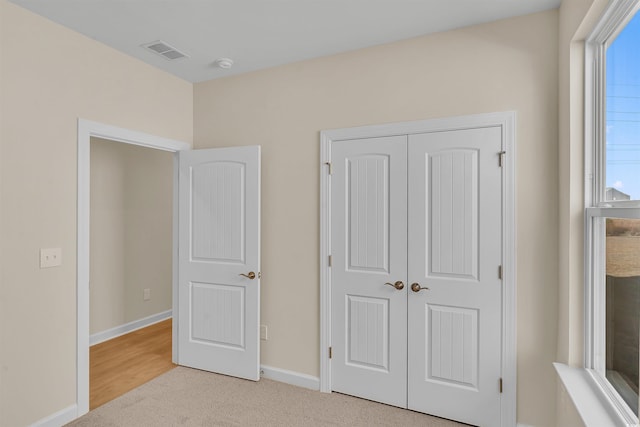 unfurnished bedroom featuring multiple windows, light colored carpet, and a closet