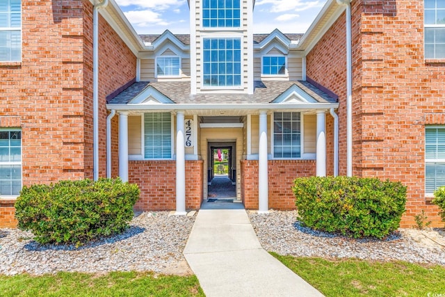 property entrance with brick siding and a shingled roof