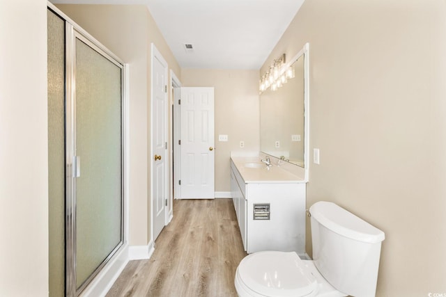 bathroom featuring a shower stall, vanity, toilet, wood finished floors, and baseboards