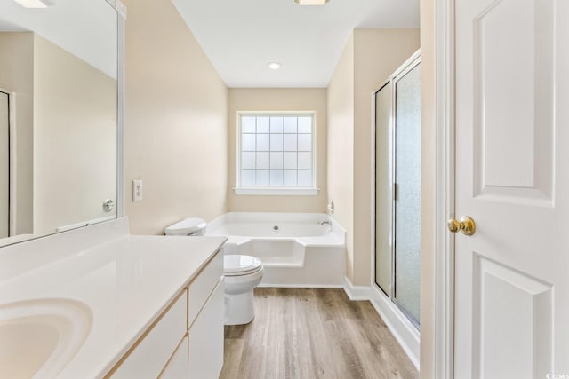 bathroom with vanity, toilet, a shower stall, a bath, and wood finished floors