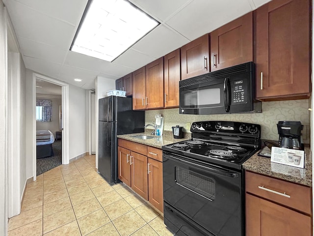 kitchen featuring light tile patterned flooring, sink, dark stone countertops, backsplash, and black appliances