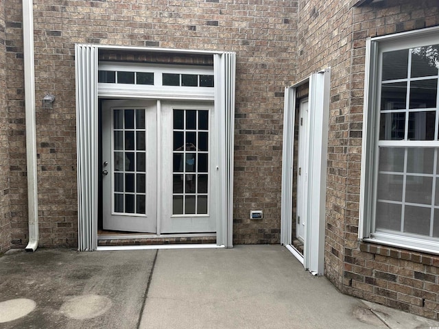 property entrance featuring french doors and brick siding