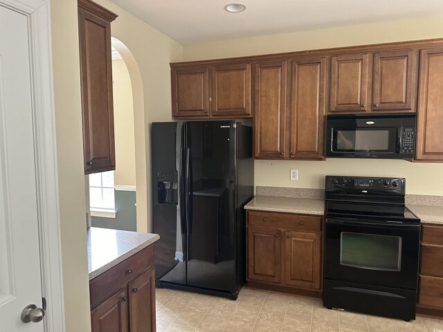 kitchen with light tile patterned flooring and black appliances