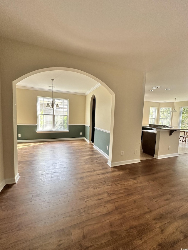 unfurnished room with a wealth of natural light, dark wood-type flooring, baseboards, and ornamental molding