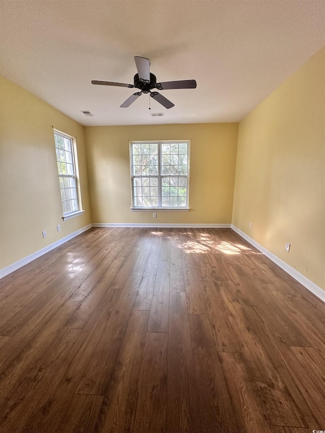 spare room with baseboards, dark wood-type flooring, and ceiling fan