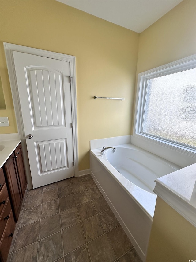 full bath featuring baseboards, tile patterned floors, vanity, and a garden tub