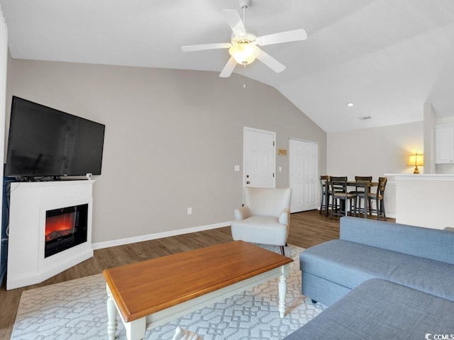 living room featuring ceiling fan, dark hardwood / wood-style floors, and vaulted ceiling