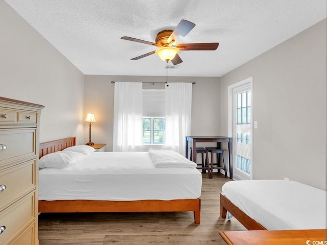 bedroom with a textured ceiling, hardwood / wood-style flooring, and ceiling fan