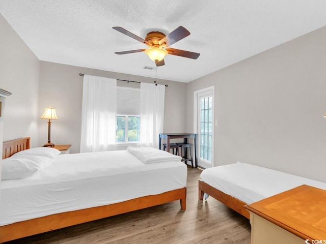 bedroom with a textured ceiling, hardwood / wood-style flooring, and ceiling fan