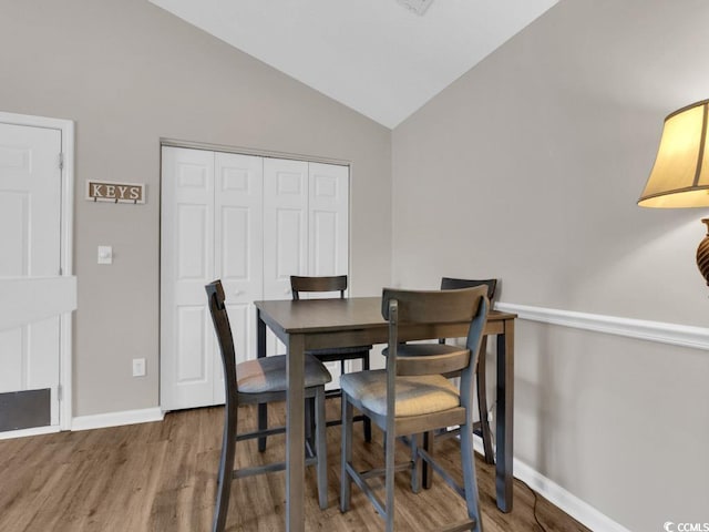 dining space with lofted ceiling and hardwood / wood-style floors