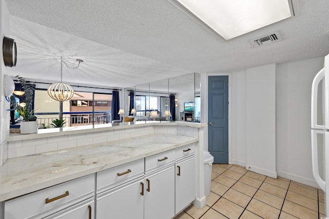 kitchen featuring light stone counters, decorative light fixtures, visible vents, white cabinetry, and light tile patterned flooring