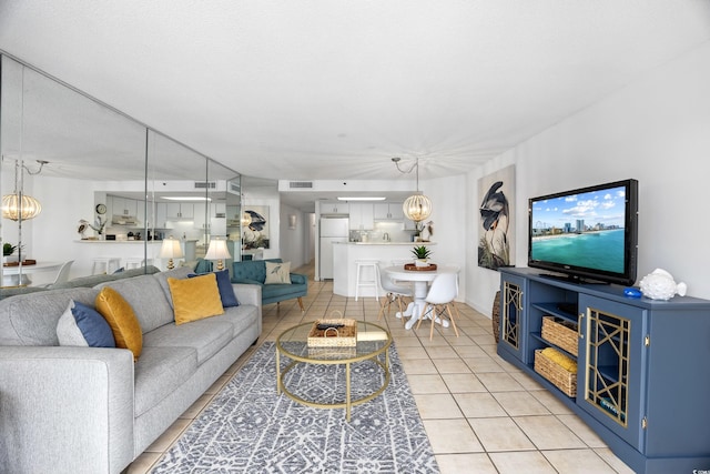 living room with light tile patterned flooring, visible vents, and a notable chandelier