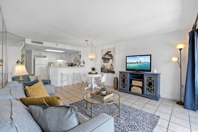 living room featuring visible vents, a textured ceiling, and light tile patterned floors