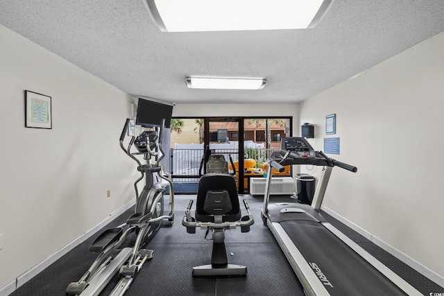 workout area featuring baseboards and a textured ceiling