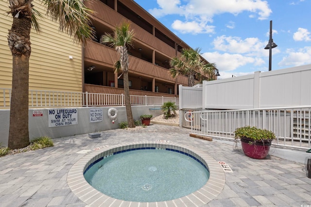 view of swimming pool with a community hot tub and fence