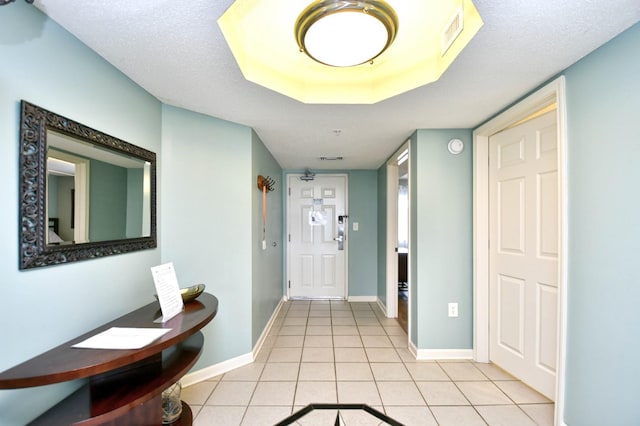 corridor with light tile patterned floors and a textured ceiling