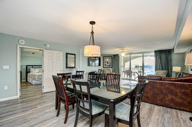 dining space with hardwood / wood-style floors, a wall of windows, a textured ceiling, and ceiling fan