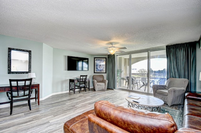 living room featuring a textured ceiling, wood-type flooring, floor to ceiling windows, and ceiling fan