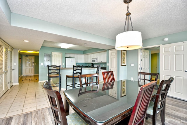 dining room featuring a textured ceiling and light wood-type flooring