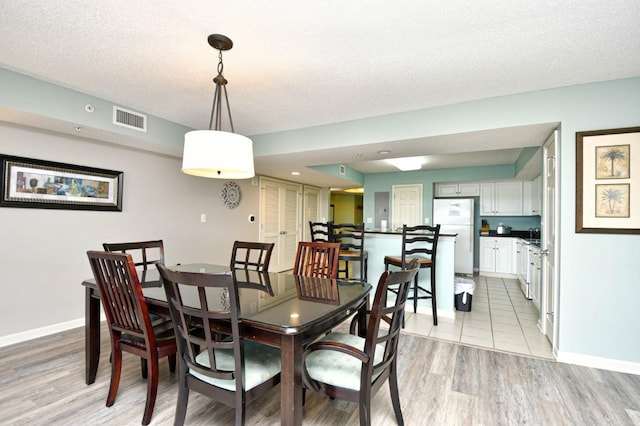 dining room with a textured ceiling and light wood-type flooring