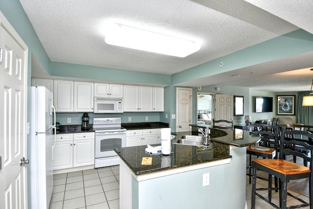 kitchen with sink, white appliances, white cabinetry, a center island with sink, and light tile patterned flooring