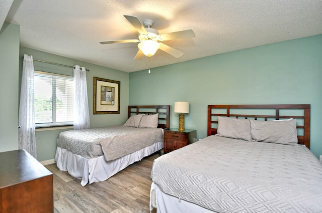 bedroom featuring ceiling fan, wood-type flooring, and a textured ceiling