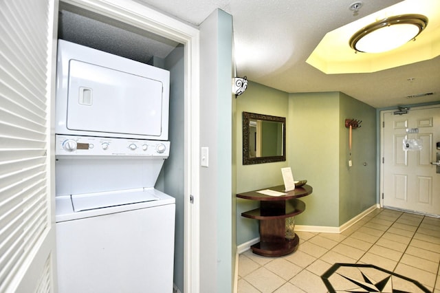 laundry room featuring stacked washer / dryer, a textured ceiling, and light tile patterned floors