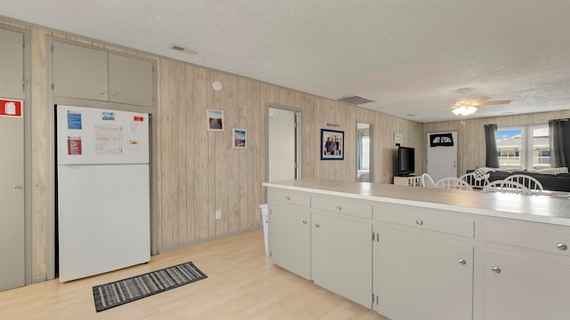 kitchen with white fridge, wood walls, light hardwood / wood-style floors, and ceiling fan