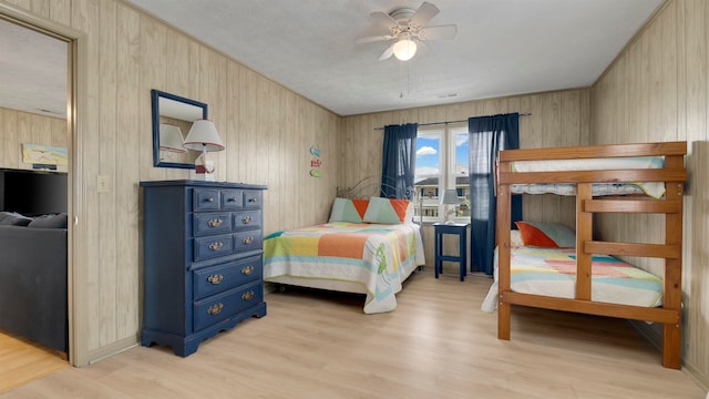 bedroom featuring wood walls, light wood-type flooring, and ceiling fan