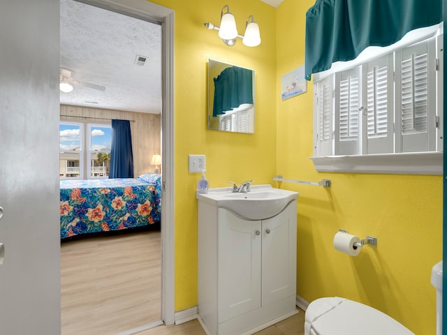 bathroom featuring hardwood / wood-style floors, a textured ceiling, toilet, vanity, and ceiling fan