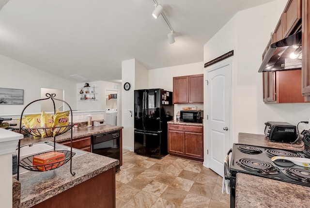 kitchen featuring vaulted ceiling, dark stone countertops, black appliances, washing machine and dryer, and track lighting