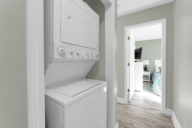 clothes washing area featuring light hardwood / wood-style flooring and stacked washing maching and dryer