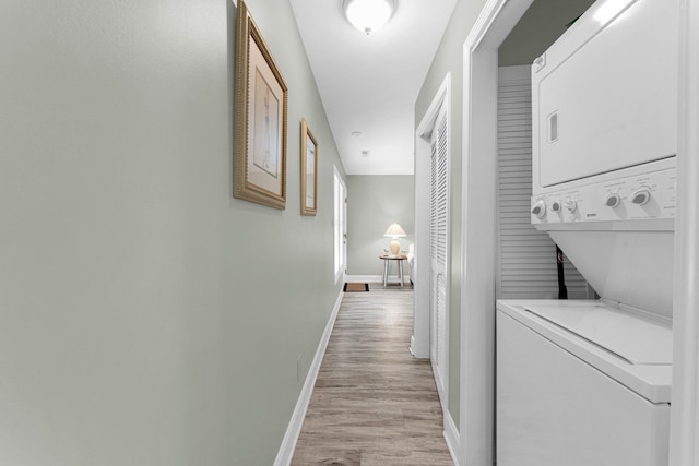 hallway featuring stacked washer and clothes dryer and light wood-type flooring