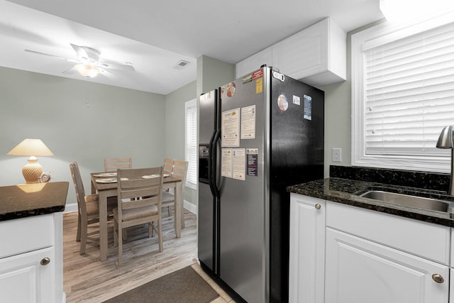 kitchen with light hardwood / wood-style flooring, stainless steel refrigerator with ice dispenser, dark stone countertops, white cabinetry, and ceiling fan