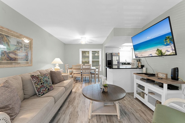 living room featuring light hardwood / wood-style floors, sink, and ceiling fan