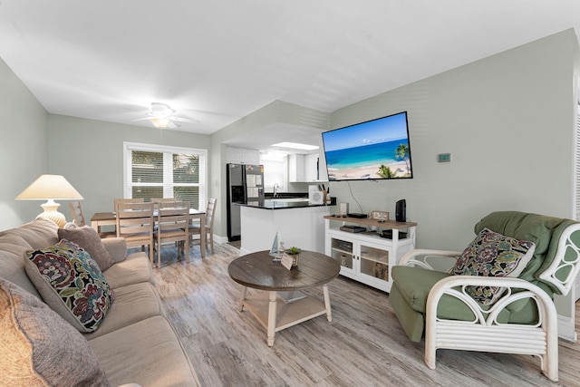 living room with ceiling fan, sink, and light hardwood / wood-style flooring