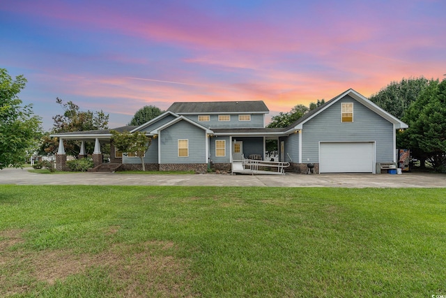 view of front of property featuring a porch, a garage, and a yard