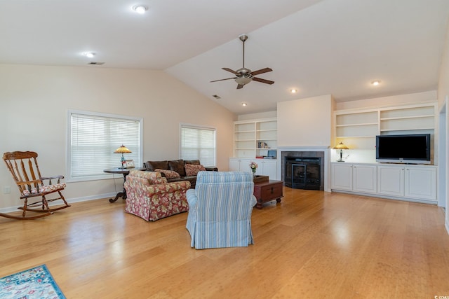 living room featuring lofted ceiling, built in features, ceiling fan, and light wood-type flooring