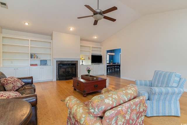 living room featuring hardwood / wood-style flooring, ceiling fan, lofted ceiling, and built in shelves