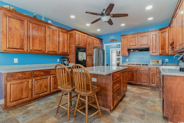 kitchen with sink, stainless steel refrigerator, a kitchen breakfast bar, a center island, and gas stovetop