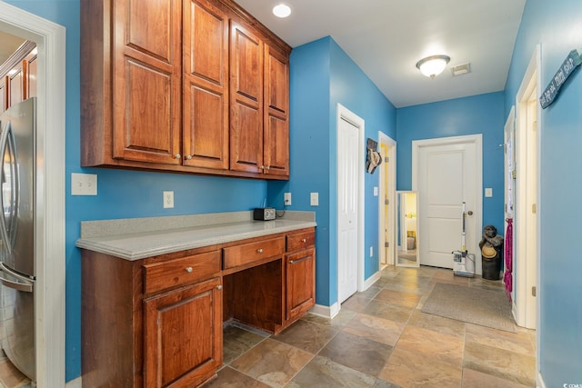 kitchen with built in desk and stainless steel fridge